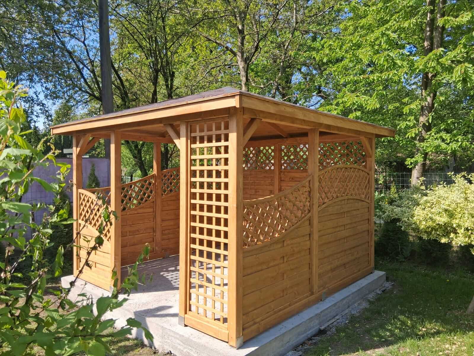 drewniana altana ogrodowa na betonowej podstawie wśród drzew